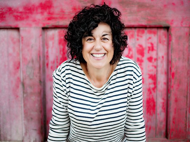 Photo of author Ann Garvin with a weathered red background.