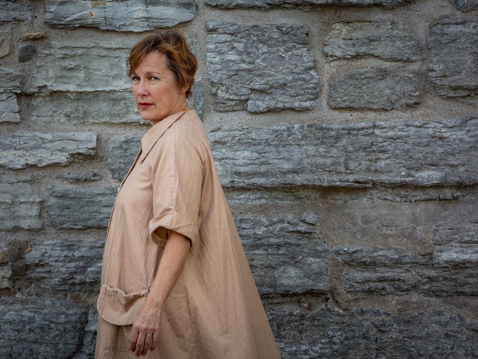 A person in front of a stone wall.