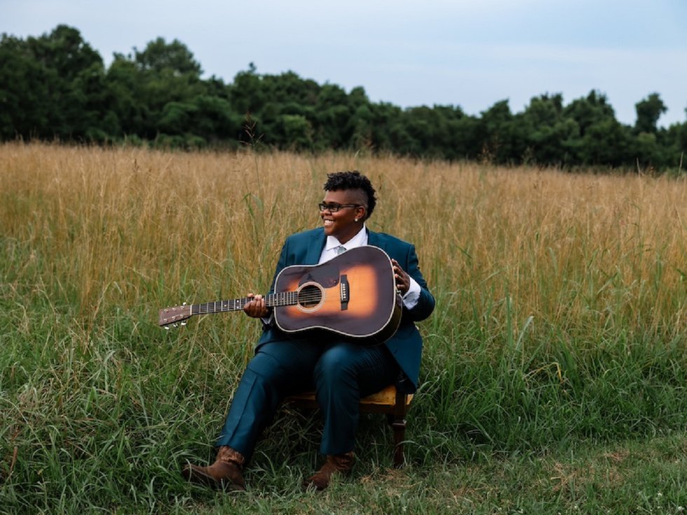Crys Matthews and a guitar in a field.