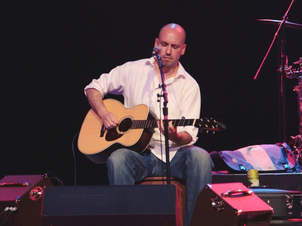 Louka Patenaude on stage playing guitar.