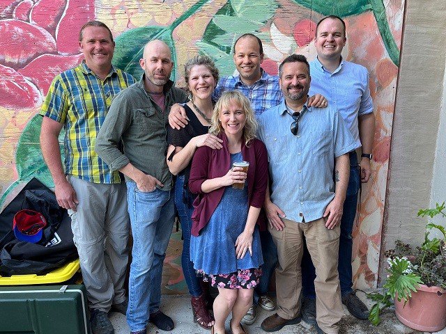 Seven-piece band The Whiskey Farm in front of a floral mural