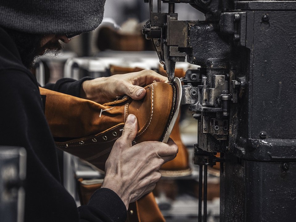 A hand holding a boot near a machine.