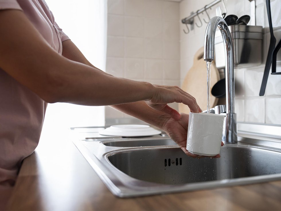A woman pouring a cup of water.