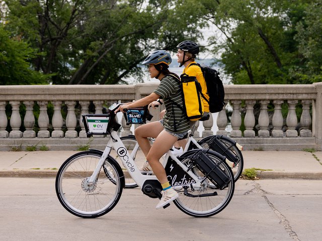 Two people riding BCycle electric bikes.